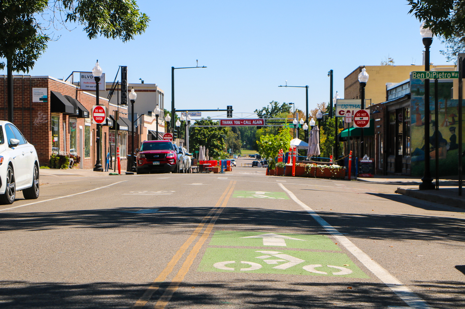 A street with a bike lane and a small commercial district in the background.