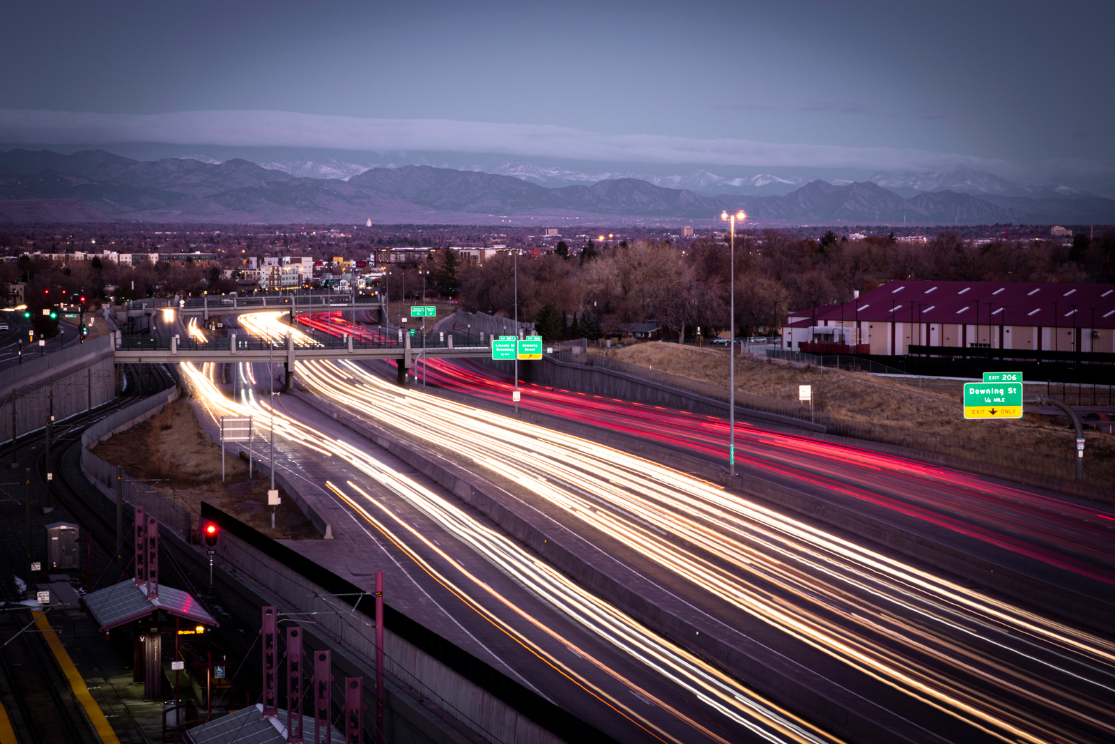 Cars on a highway at dusk with motion blur headlights and mountains in the background.