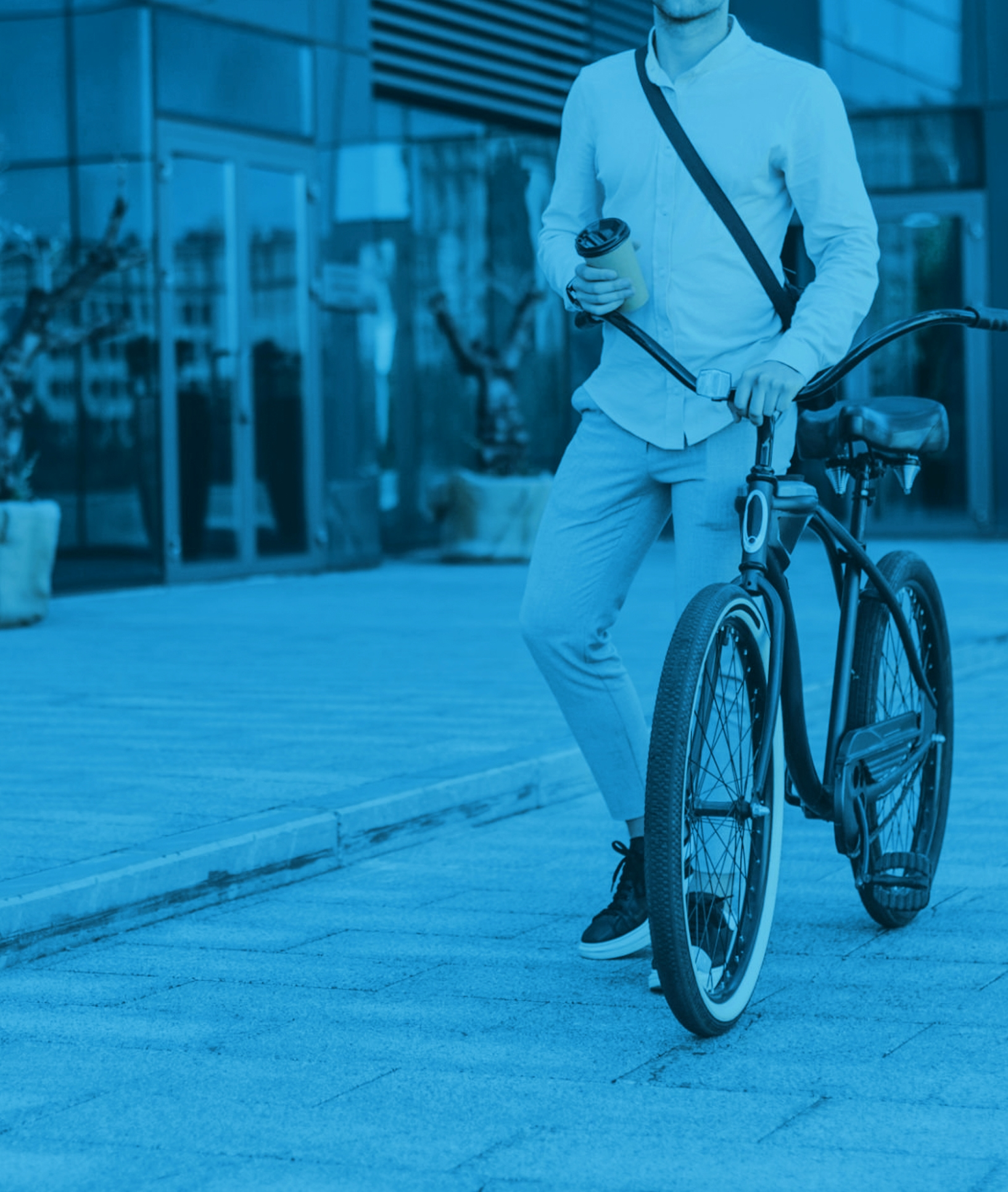 A person holding a cup of coffee while standing beside a bicycle