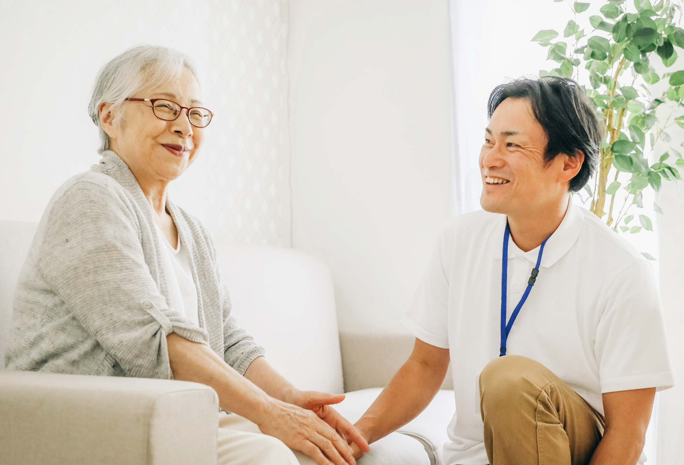 An older adult woman smiles while talking with a younger man about volunteer opportunities.